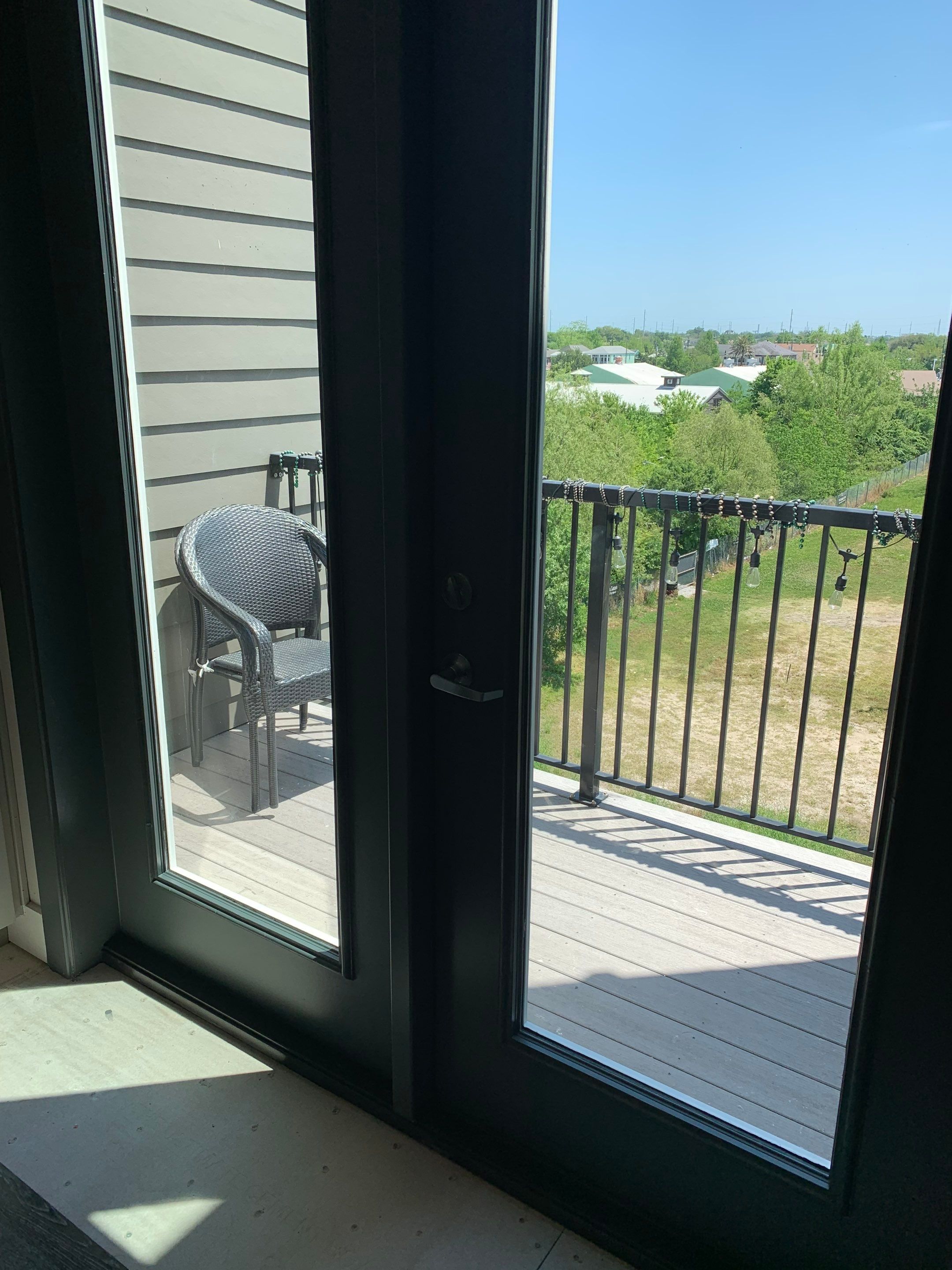 Interior view through the replacement French doors toward the balcony, showing the new dark-finished door assembly.