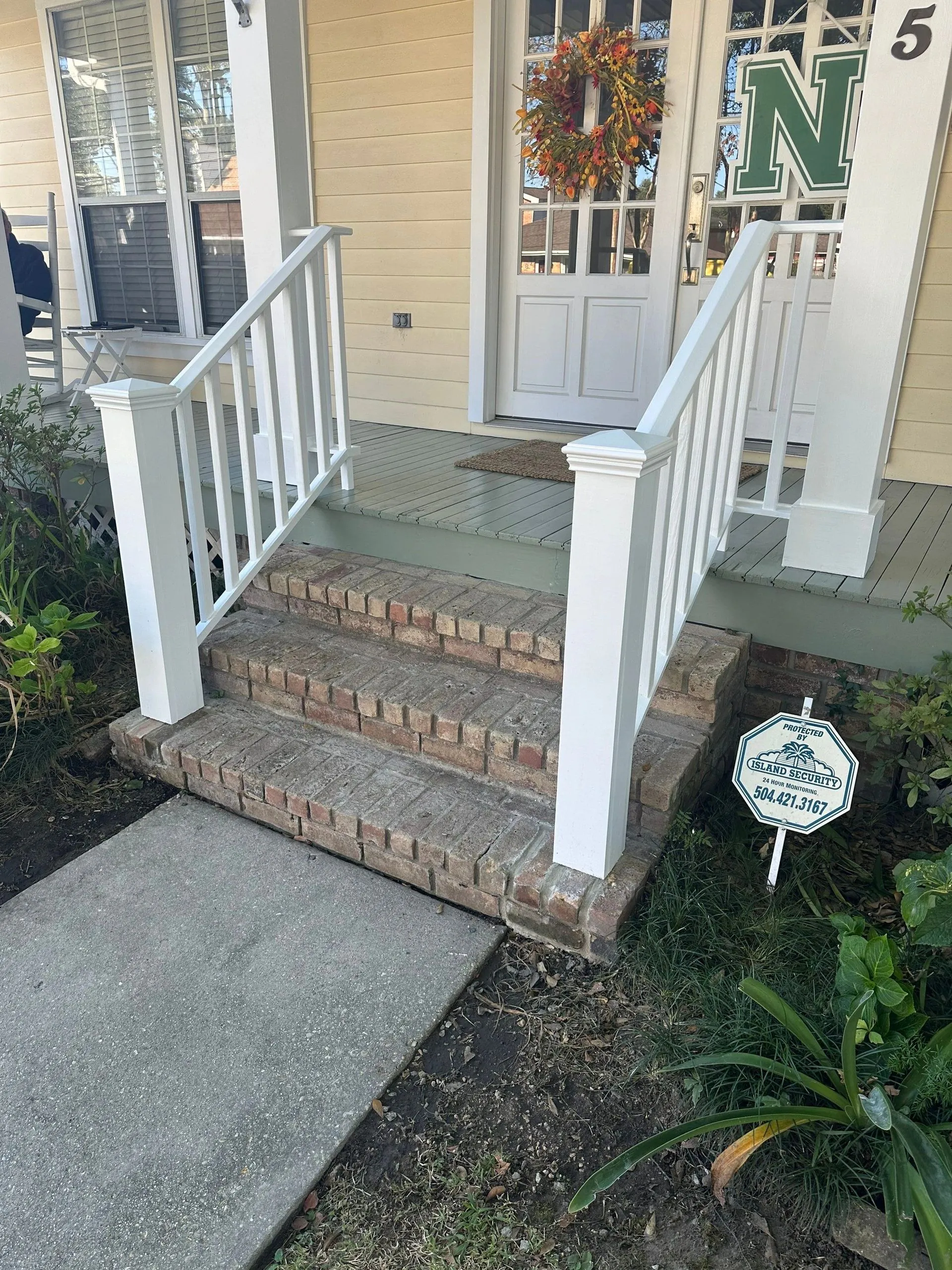 Front brick steps and porch of a raised New Orleans home with new handrails