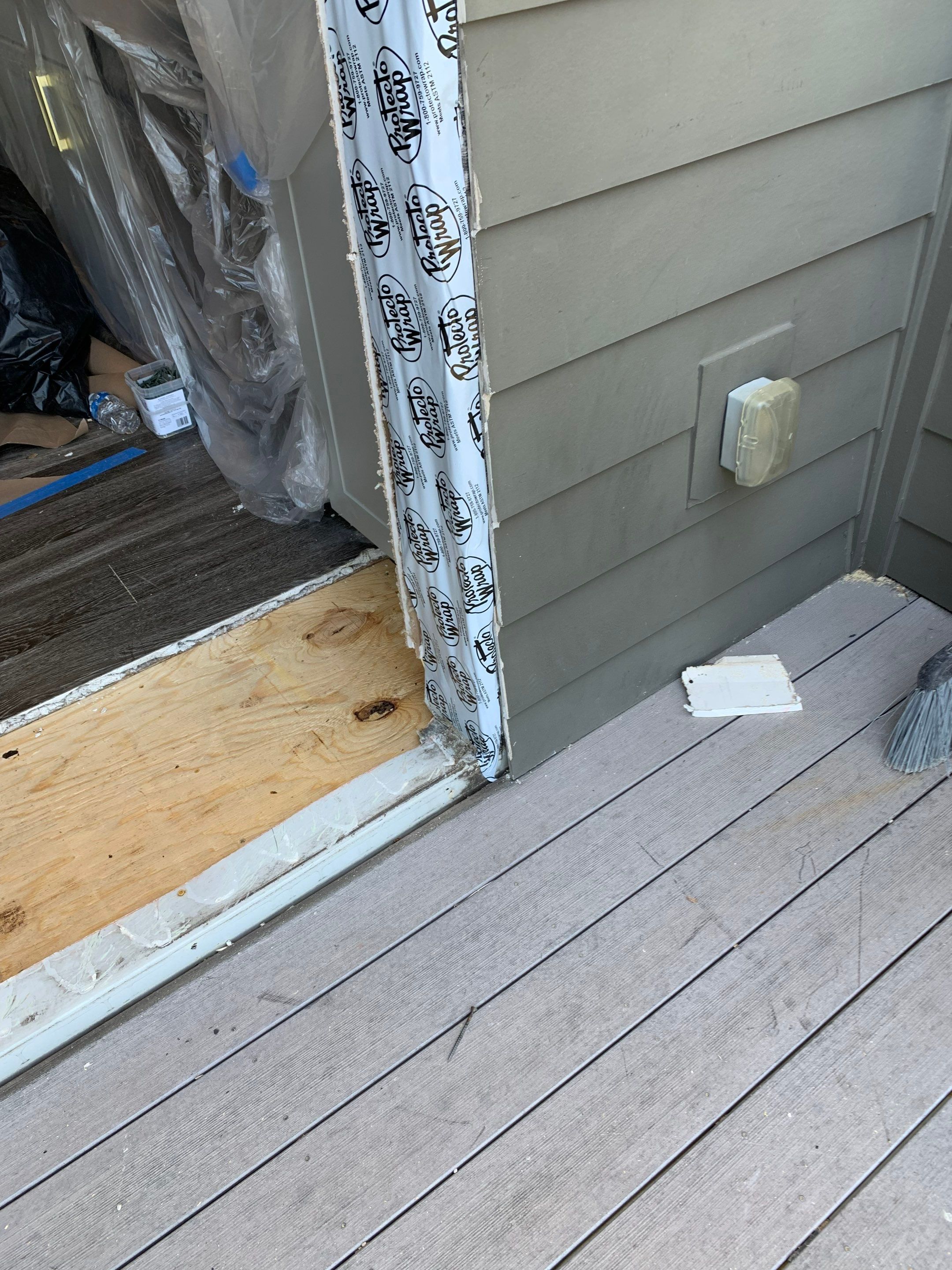 Balcony-side view of the replacement subfloor and weather-resistant barrier along the jamb.
