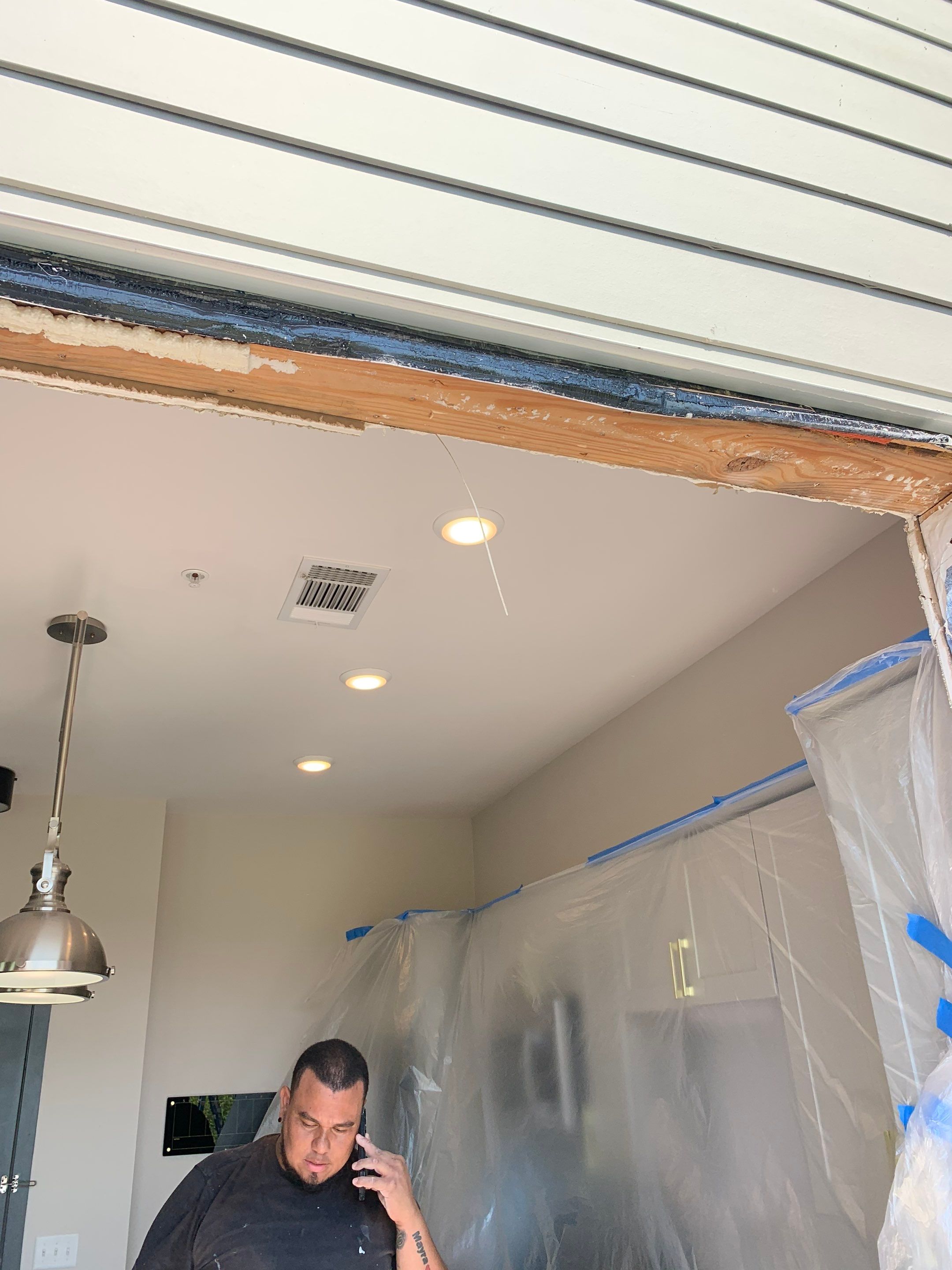 Interior view of the exposed door header with surrounding kitchen cabinets protected during construction.