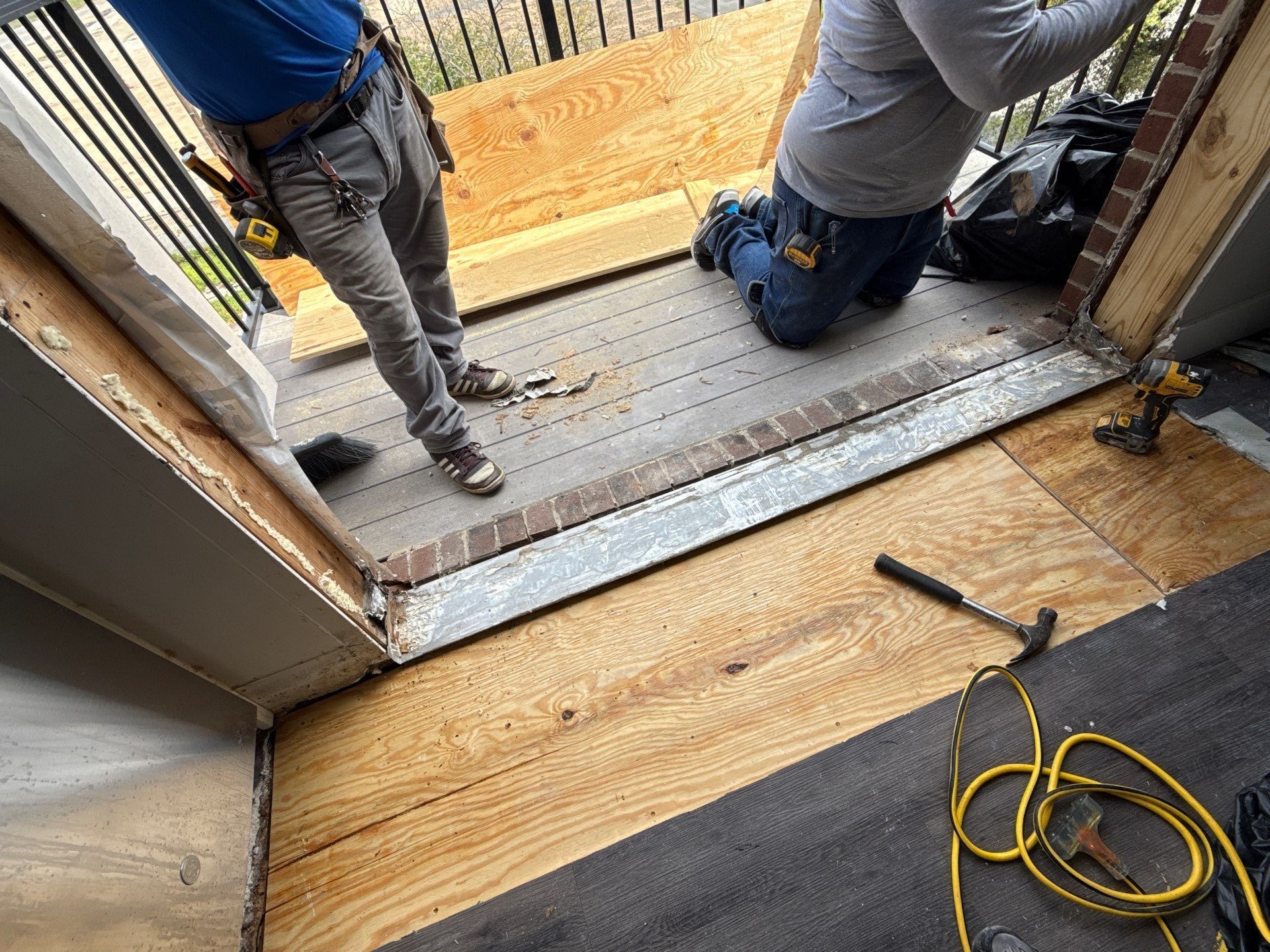 Crew working at the balcony opening after subfloor replacement and removal of the original doors