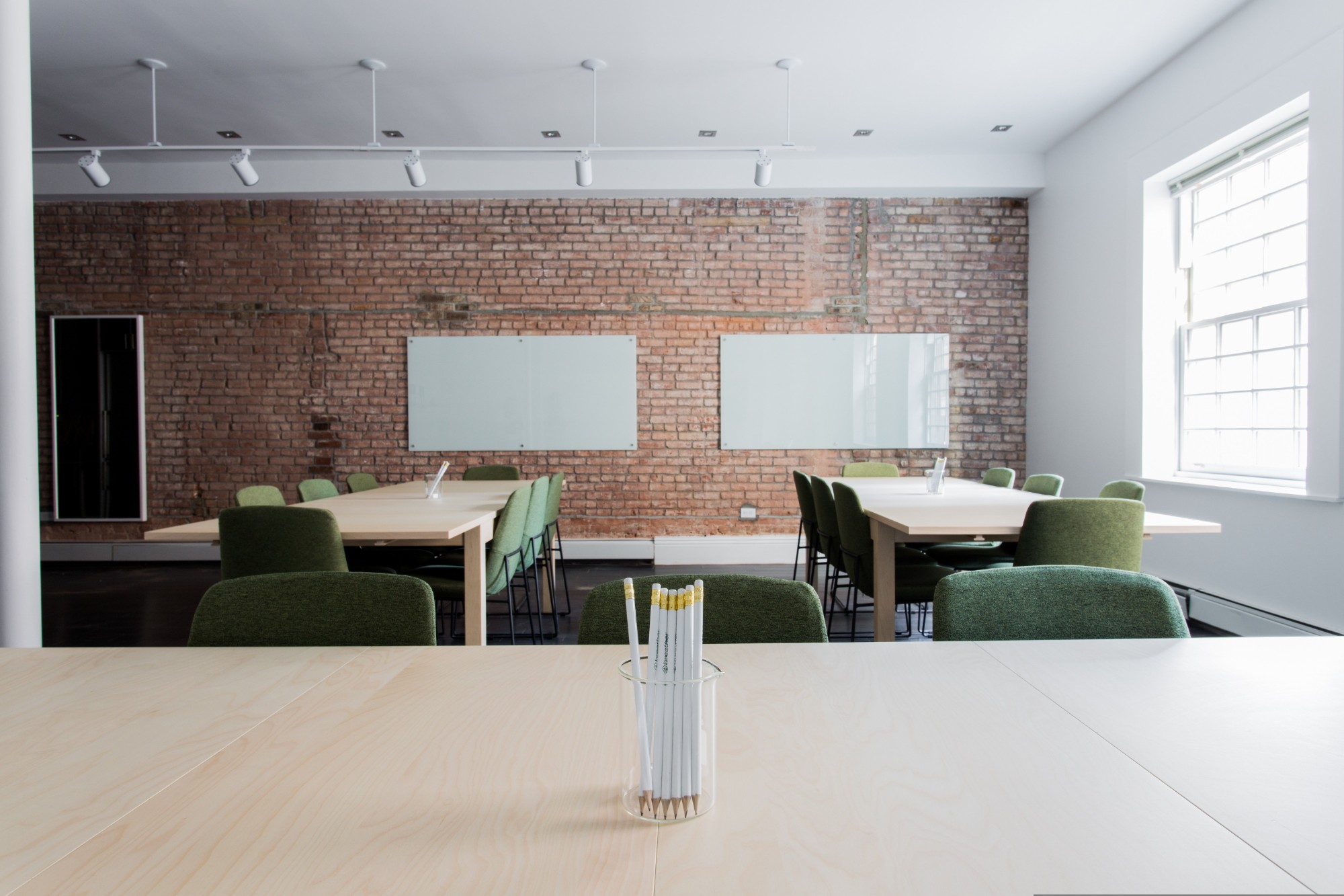 Renovated office with exposed brick wall, glass whiteboards and work tables