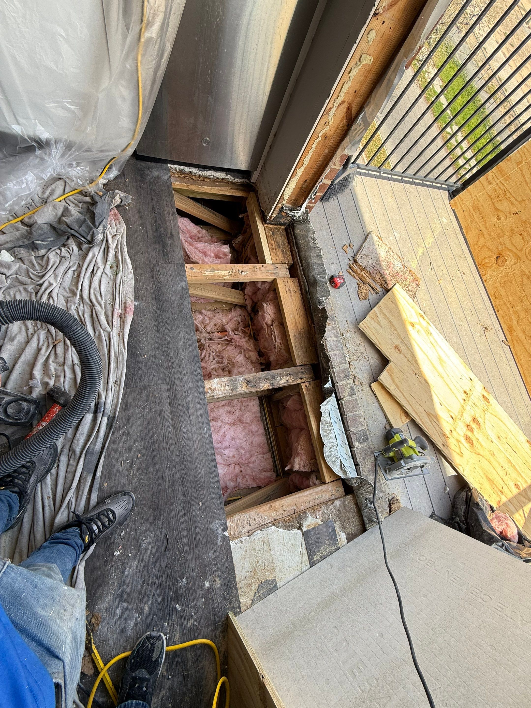 Wider view of the opened floor assembly, showing the framing and insulation beneath the damaged entrance area