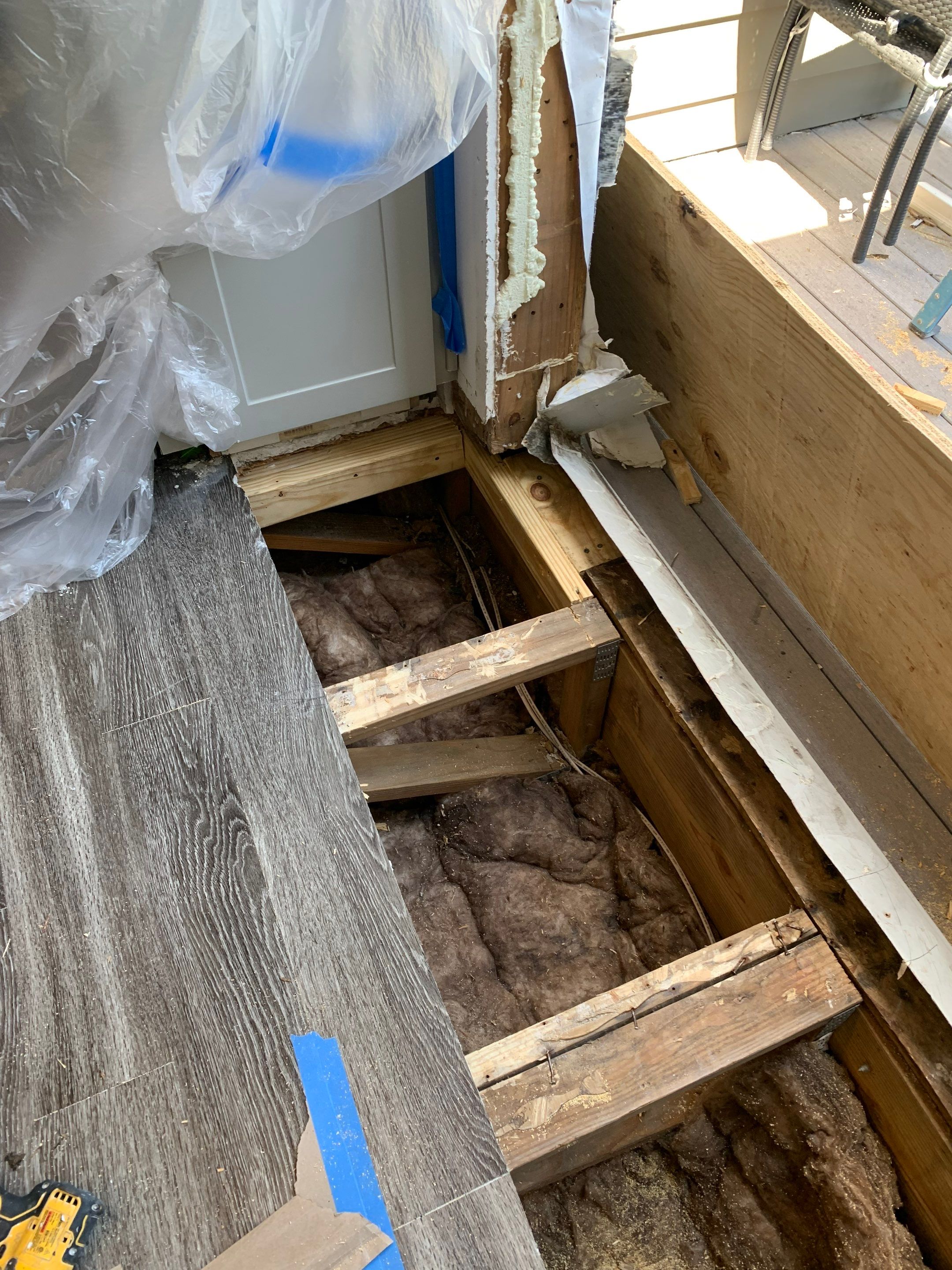 Wider view of the opened floor assembly during structural repairs near the balcony entrance.