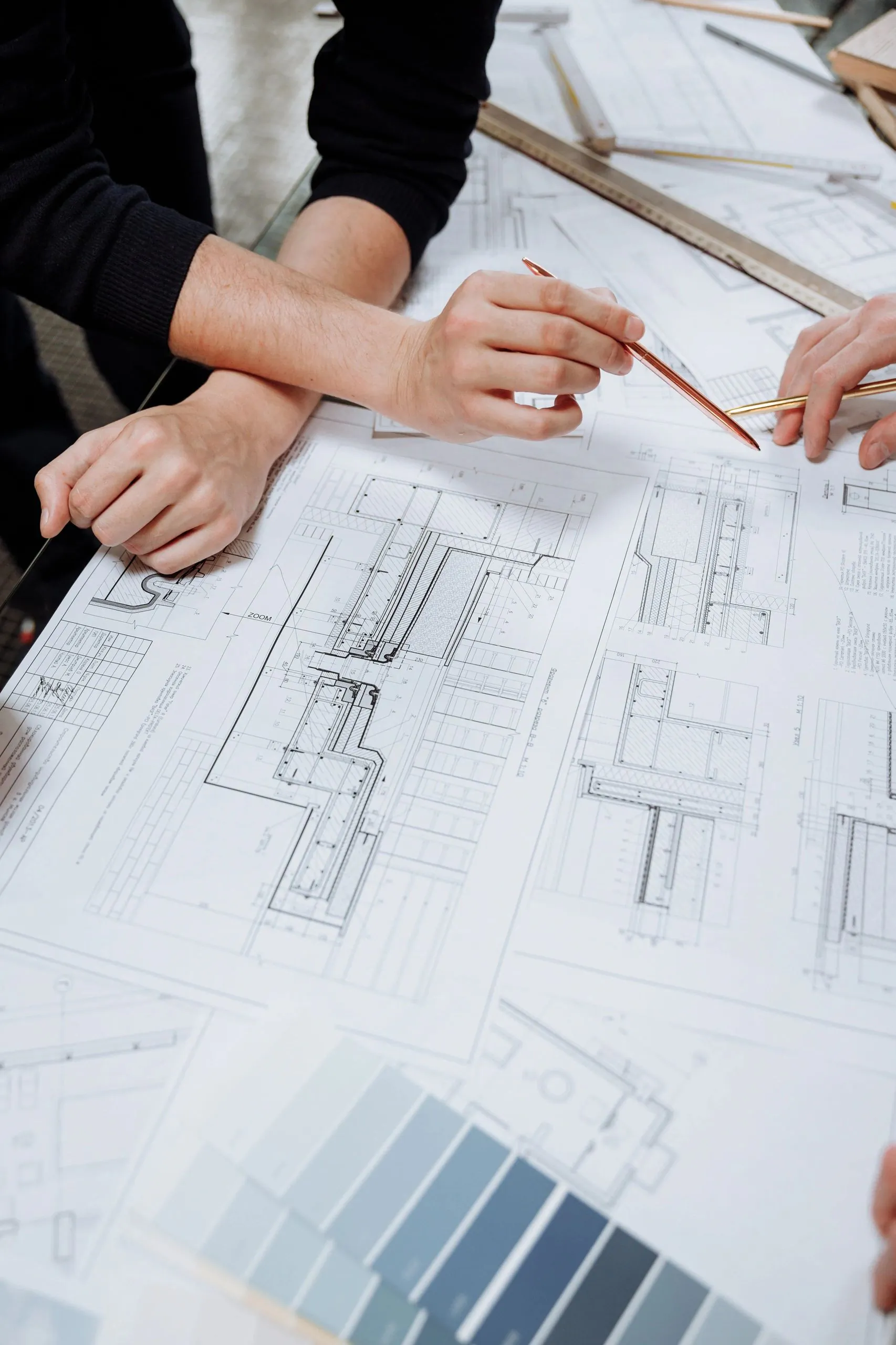 Two people discussing architectural blueprints with pencils.