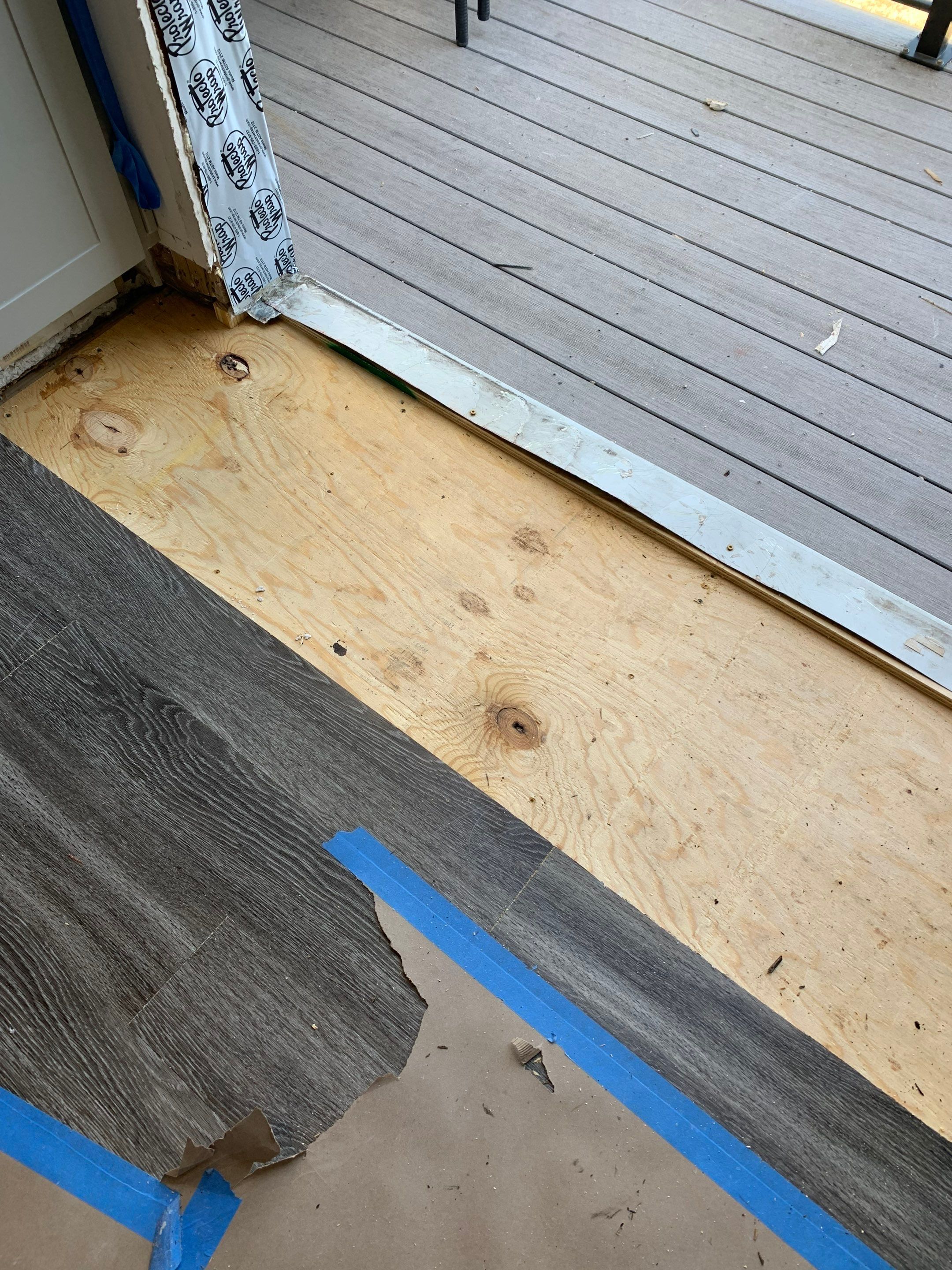 New plywood subfloor installed at the balcony doorway, restoring the floor surface after repairs.