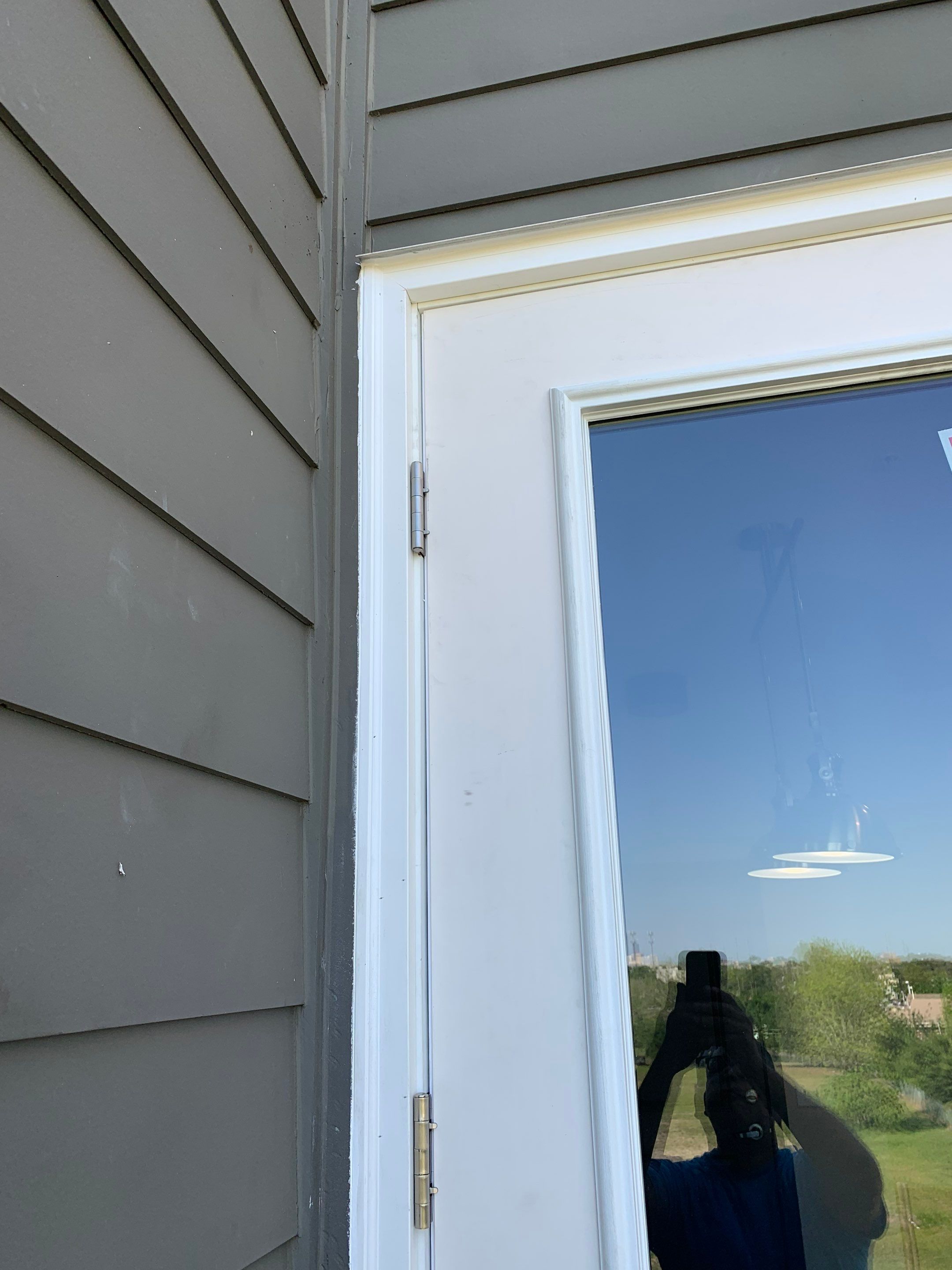 Upper exterior corner of the replacement balcony door showing its finished frame and trim.
