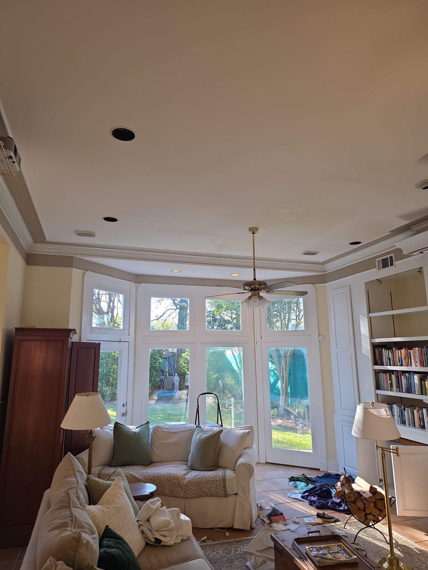 A wider view of the downstairs den before ceiling reconstruction, showing the existing finishes and architectural features.