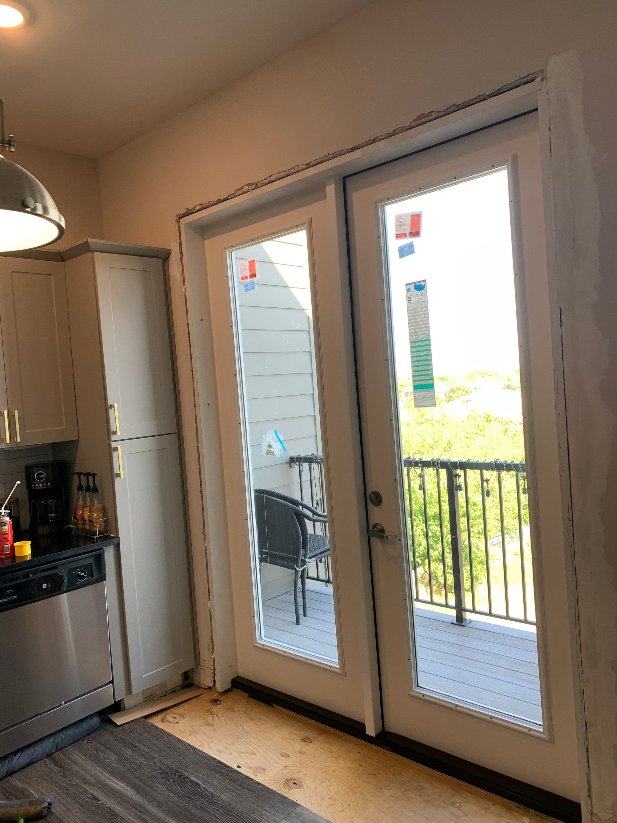 New French doors installed at the kitchen balcony entrance, with interior finish repairs still to be completed.