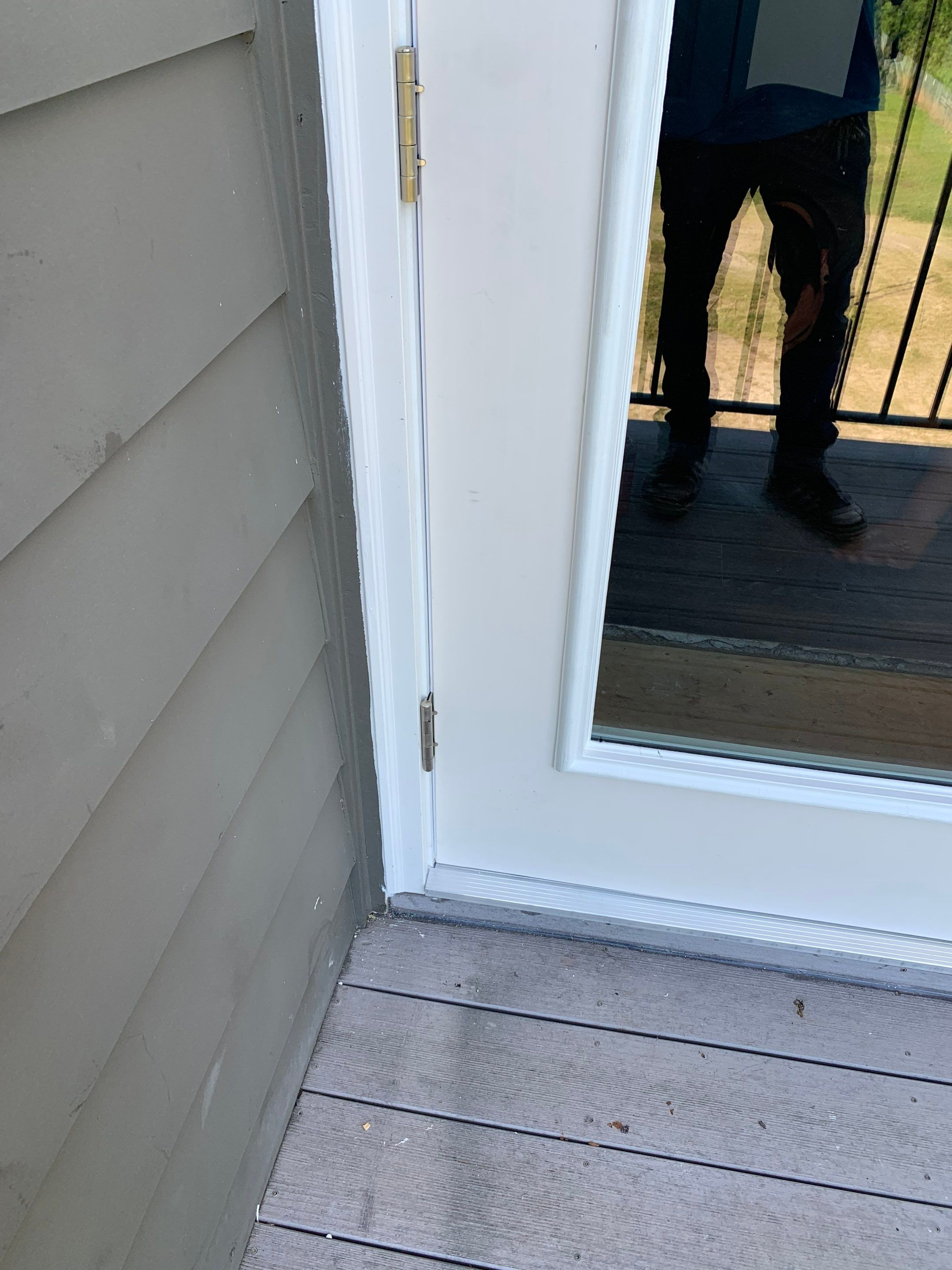 Lower exterior corner of the newly installed balcony door with surrounding trim and siding restored.