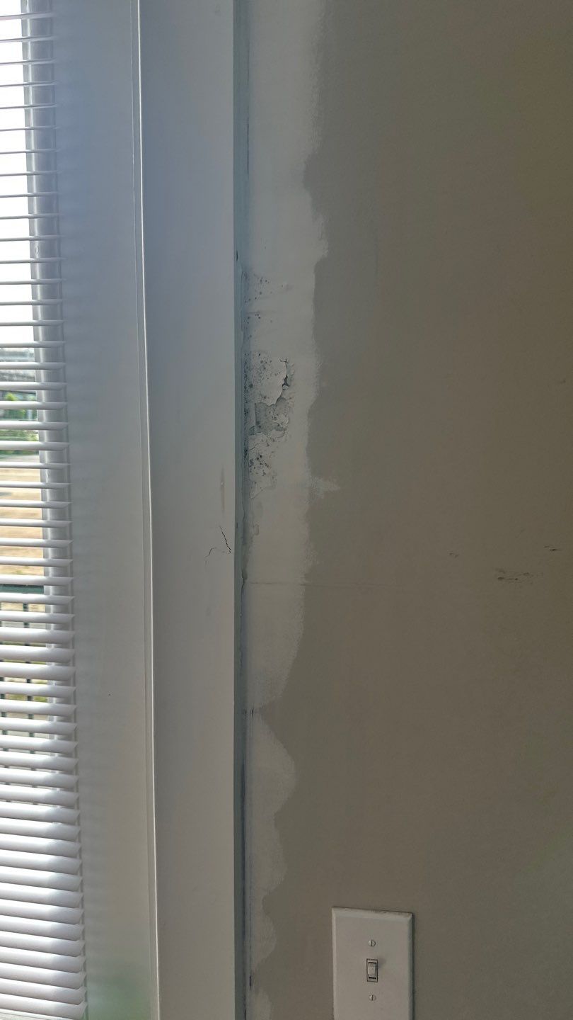 Discolored and patched wall alongside door casing
