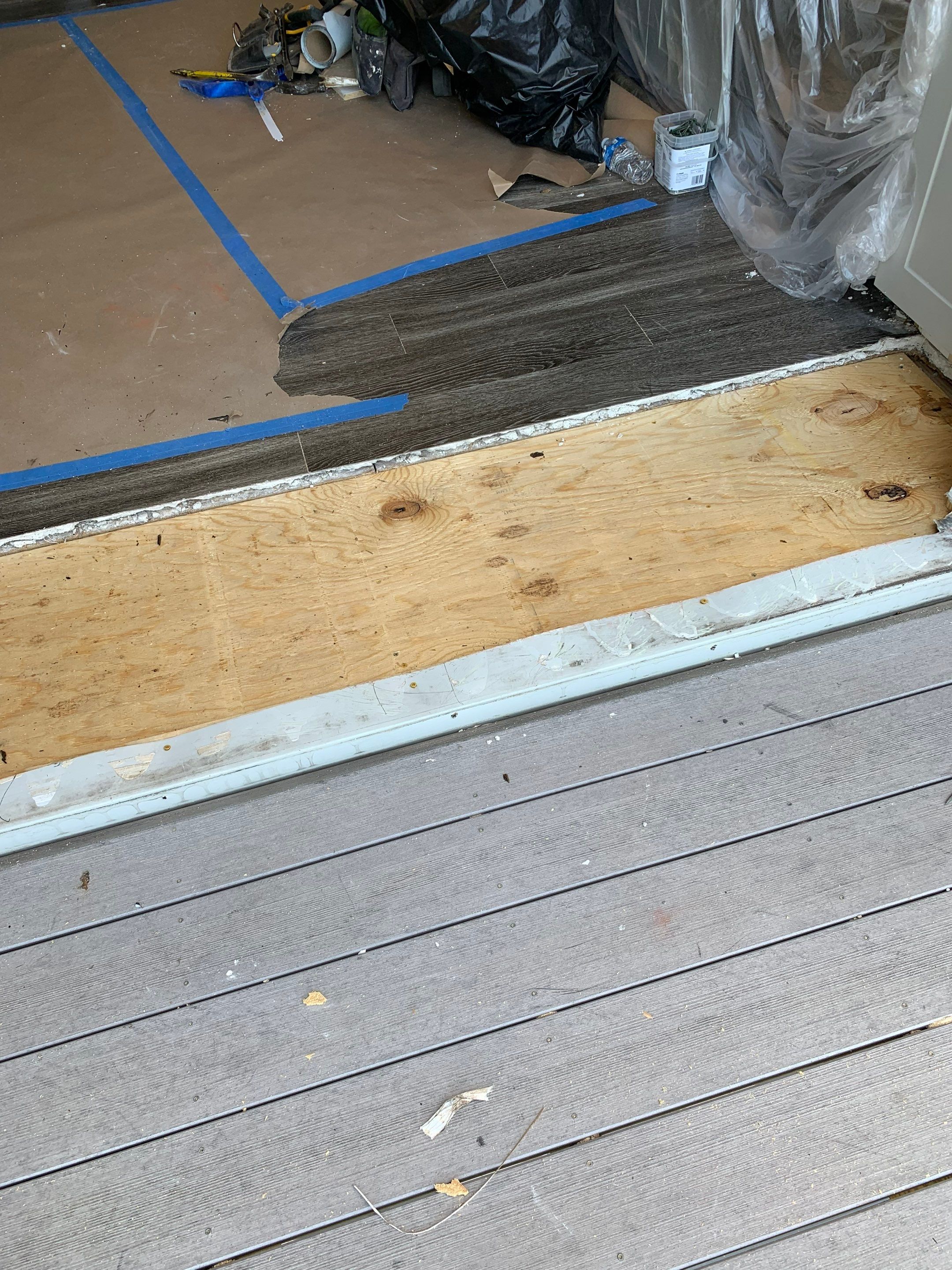 Repaired threshold area showing new plywood subfloor and the adjoining original flooring.
