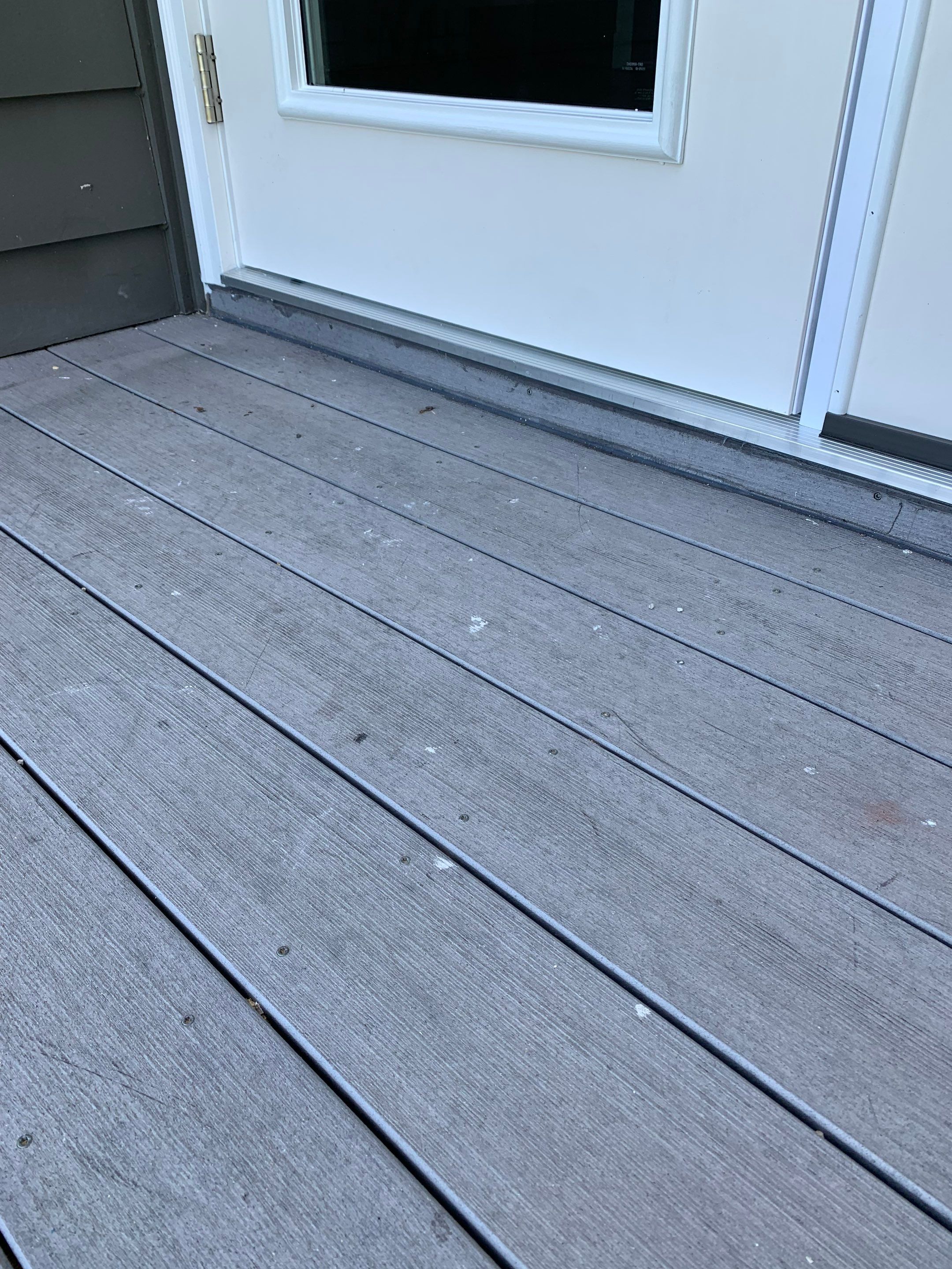 Completed exterior threshold where the replacement door meets the balcony decking