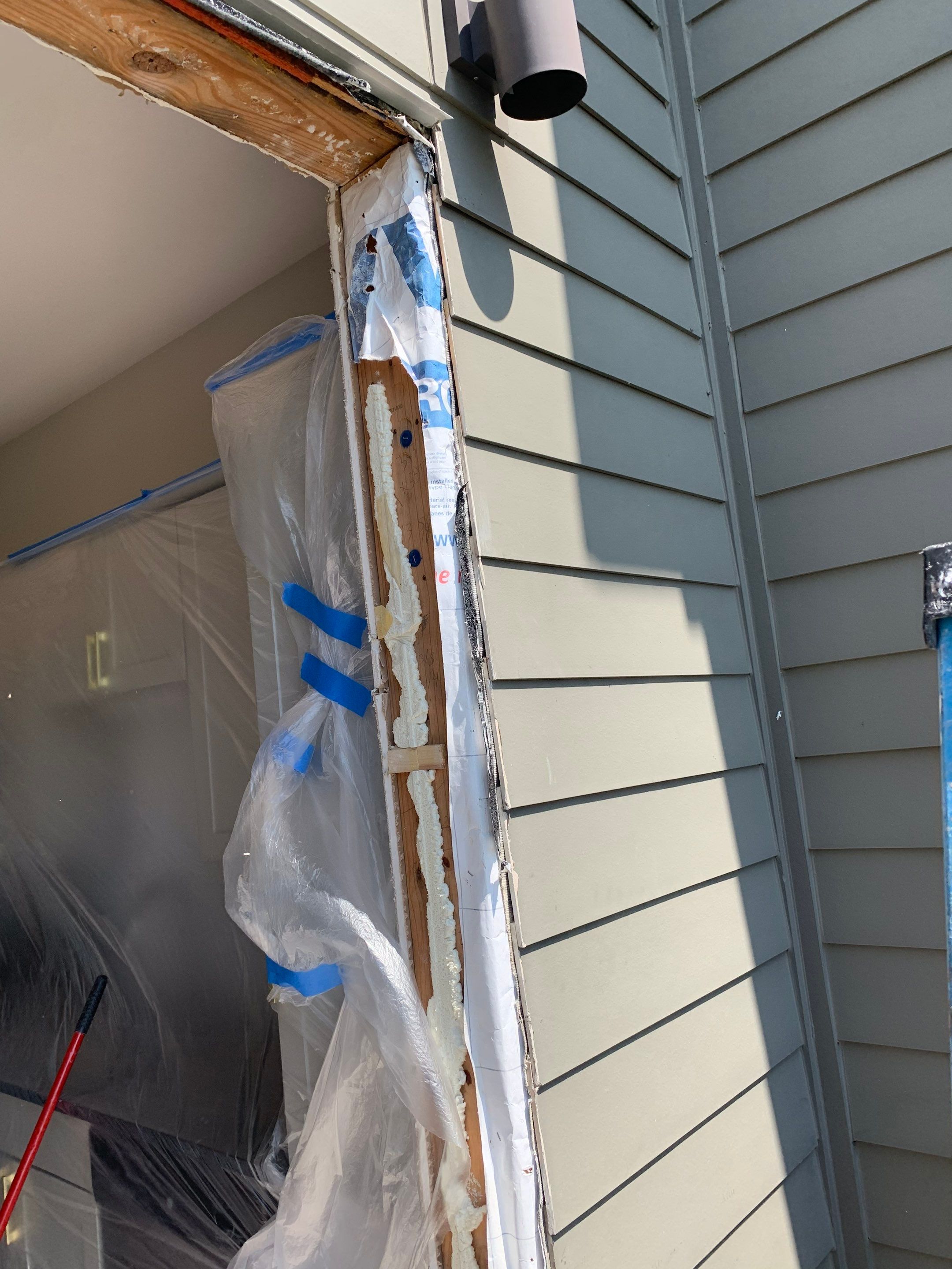 Exterior jamb framing and weather barrier exposed as the opening is prepared for the replacement doors.