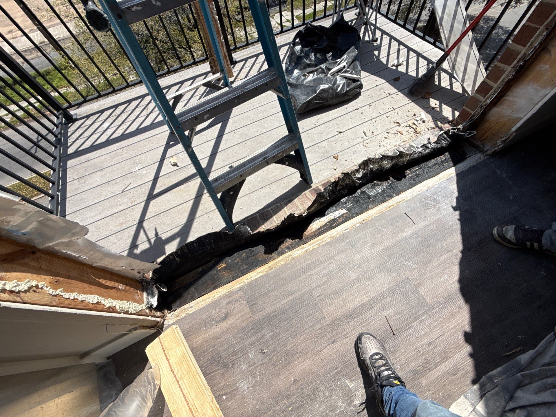 Torn threshold material exposed at floor-to-balcony transition