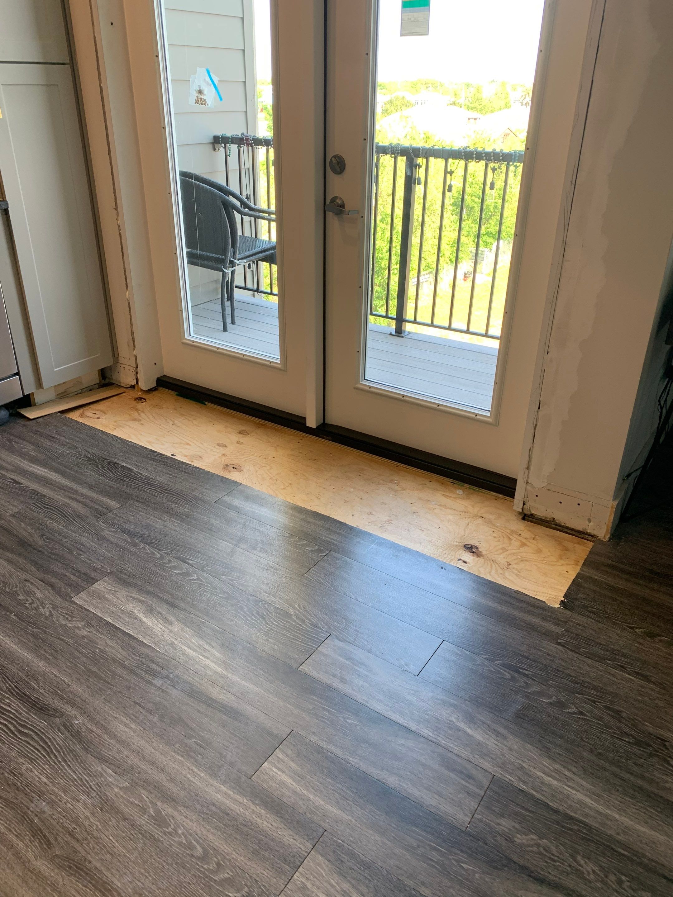 Interior view of the newly installed balcony doors, with flooring restoration still underway.