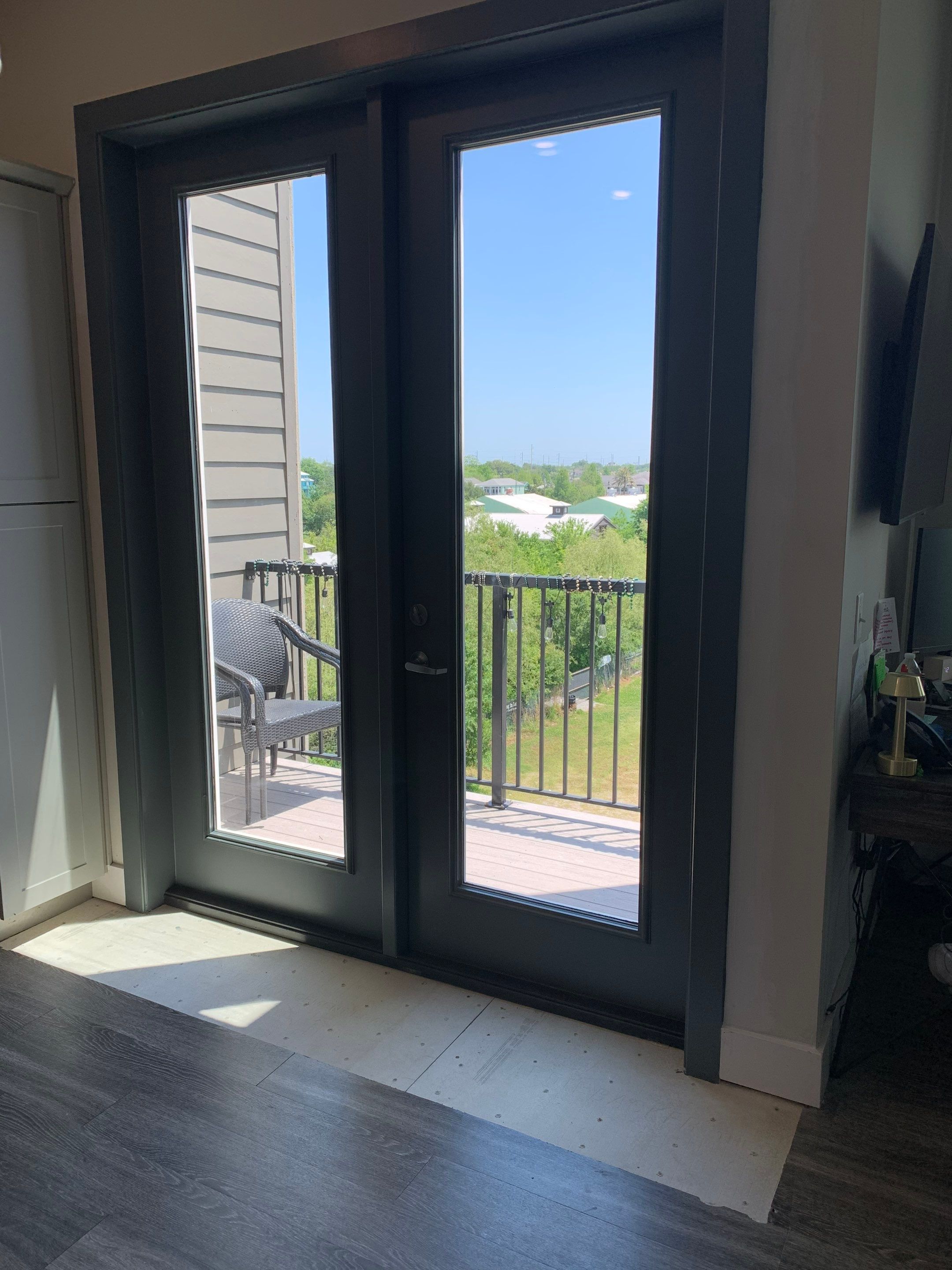 Wider interior view of the replacement French doors and completed surrounding trim, with the balcony visible beyond.