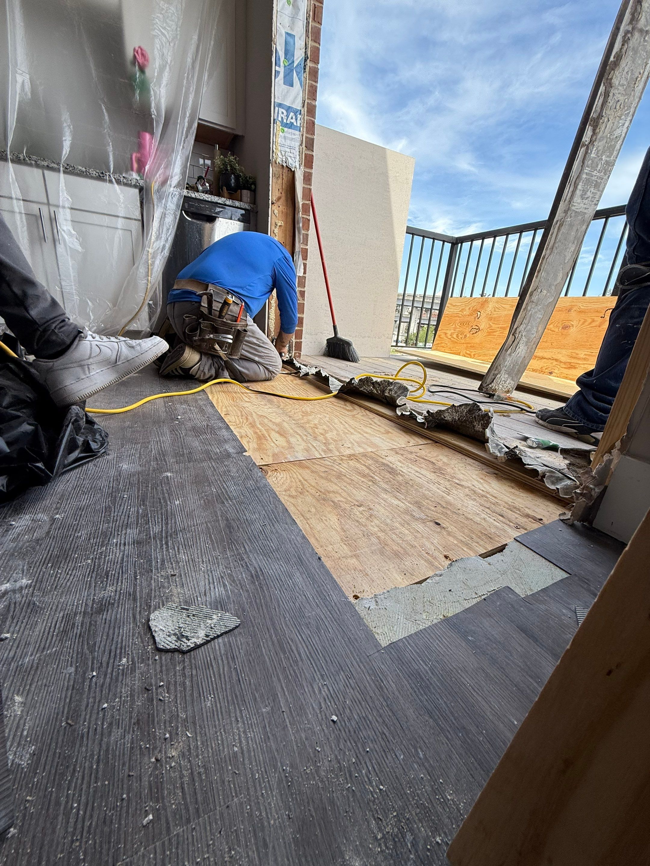 Workers preparing the repaired floor and balcony entrance for the replacement French door installation