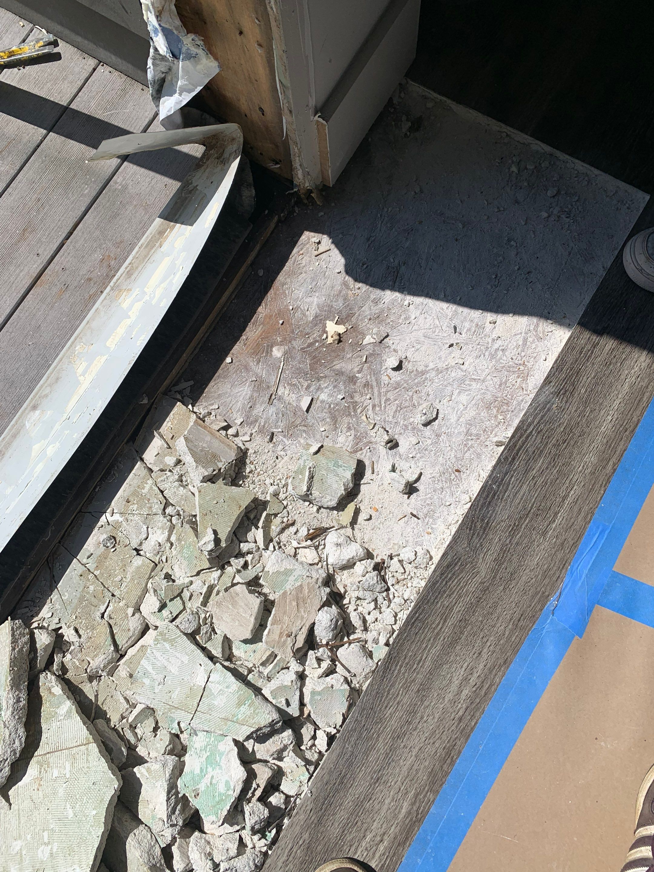 Additional demolition at the doorway exposes deteriorated material beneath the original flooring.
