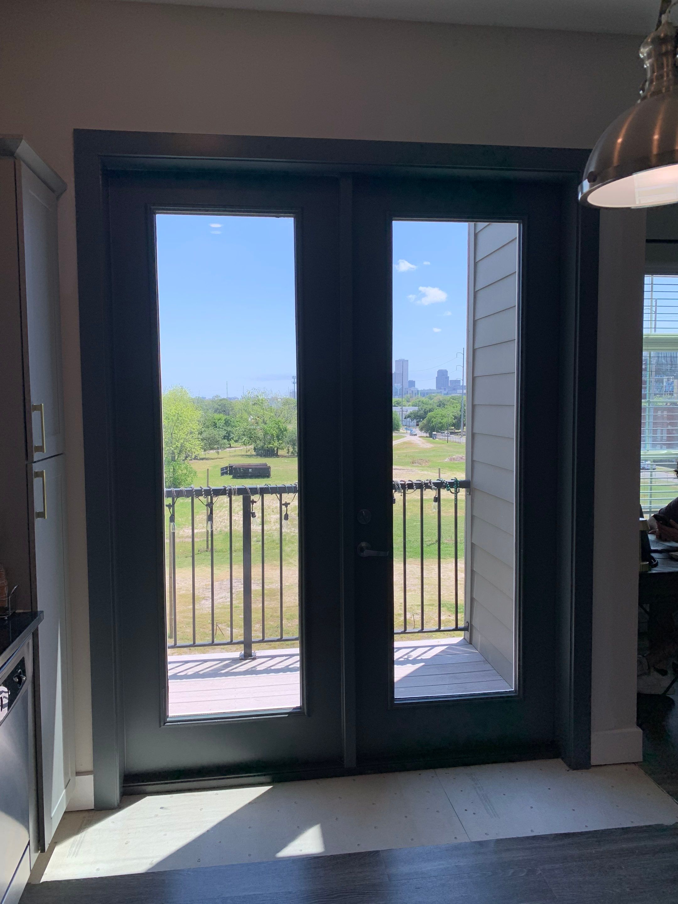 Completed dark-finished French doors at Lumina Apartments, replacing the original balcony entry with a refreshed appearance.