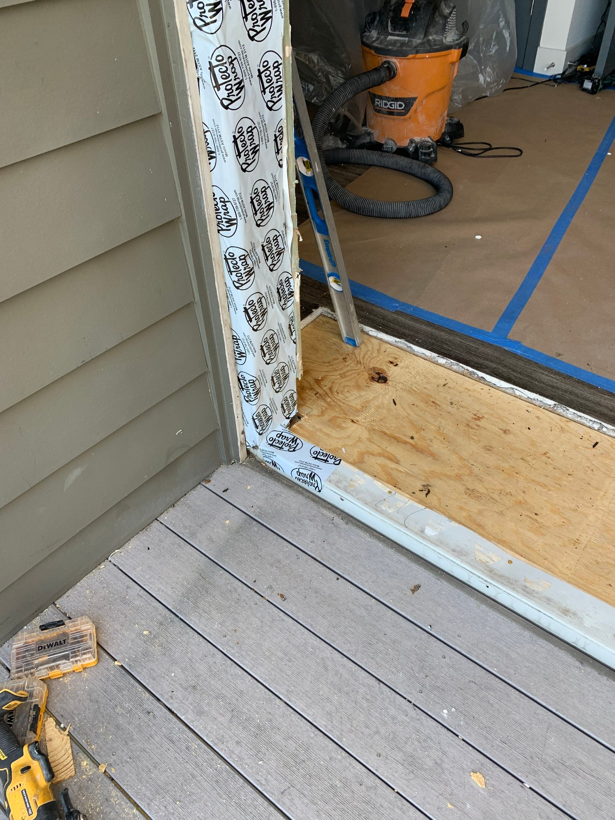 Exterior view of the repaired threshold area showing new plywood and exposed door jamb preparation.