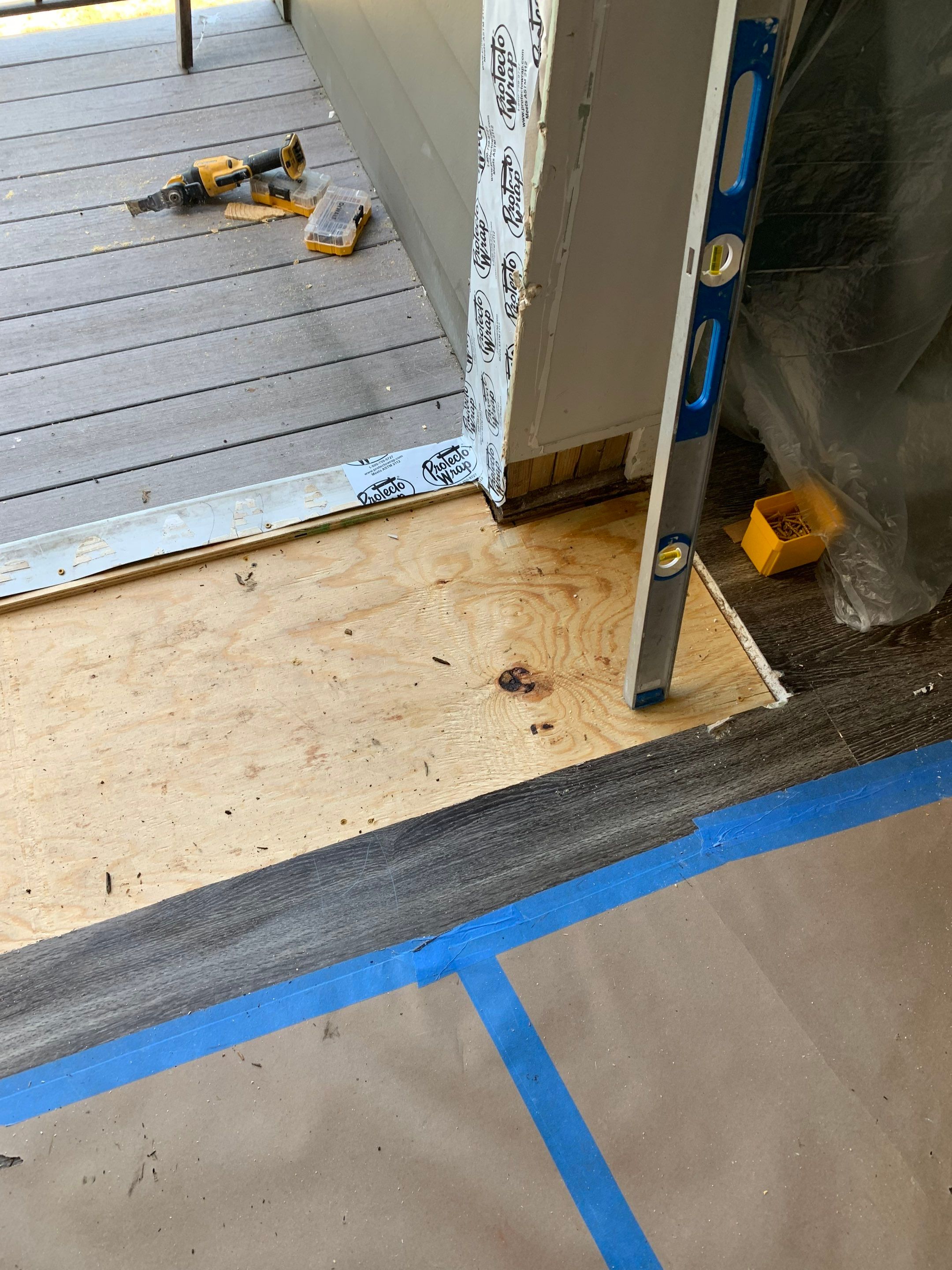 Replacement plywood fitted around the doorway, with surrounding flooring protected from construction activity.