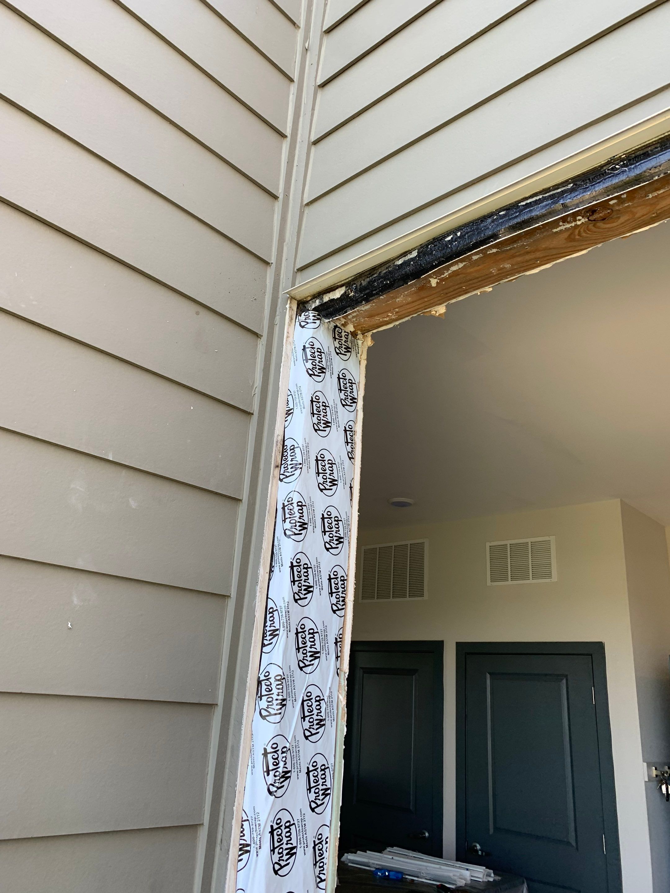 Upper exterior corner showing weather barrier preparation and exposed framing before door installation.